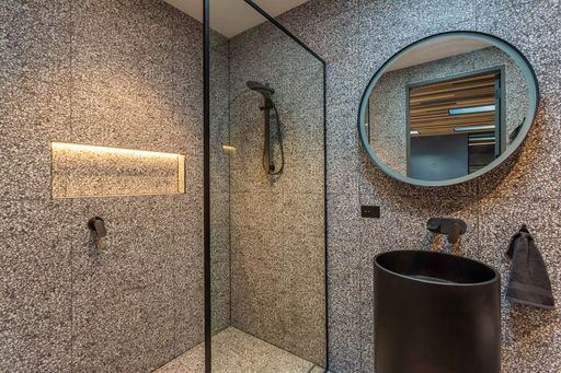 Tiled walk-in shower and vessel sink in a completed bathroom remodel