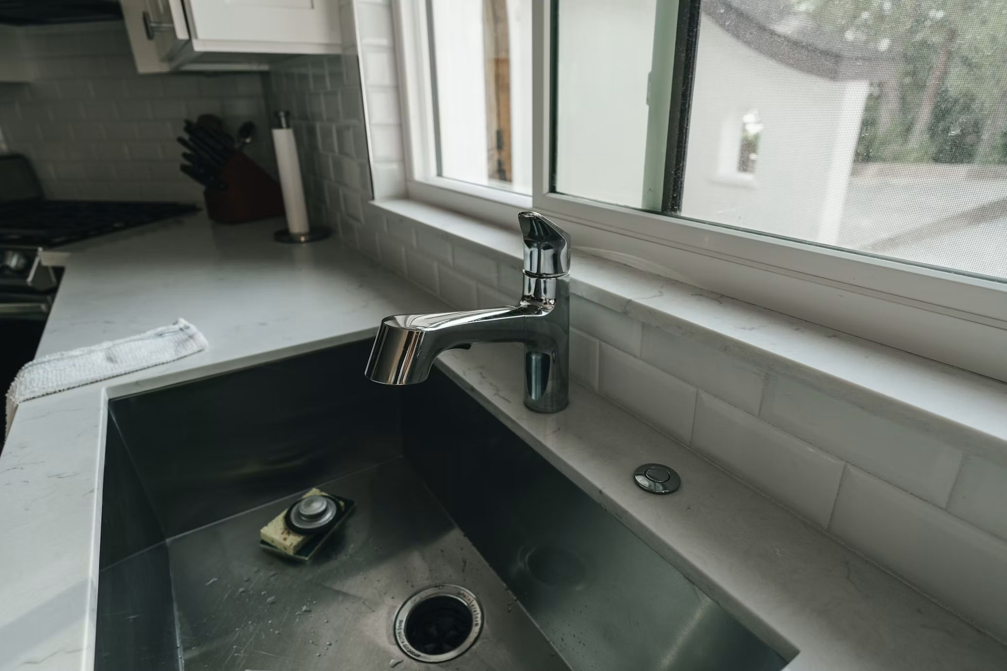 Undermount kitchen sink and faucet being serviced by a window
