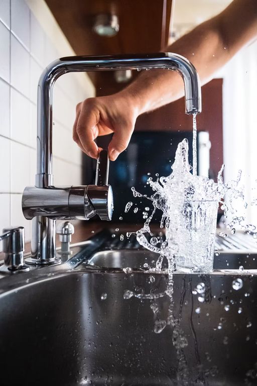 Water running hard from a kitchen faucet into a stainless sink